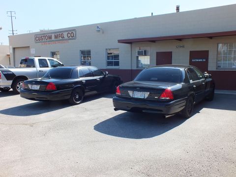 2003 Ford Crown Victoria - Black Crown Victoria EVIL VIC and a twin sedan with a white pickup at the Custom Mfg Co lot.