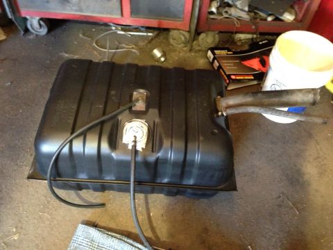 1979 Ford Bronco - A black fuel tank with attached hoses and a sender unit is visible on a garage floor.