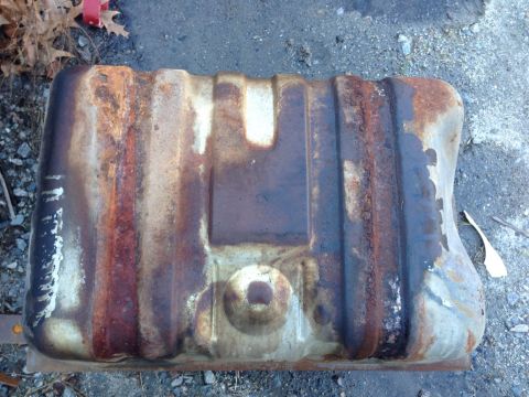 1979 Ford Bronco - This heavily rusted fuel tank is shown from above, resting on a gravelly surface.