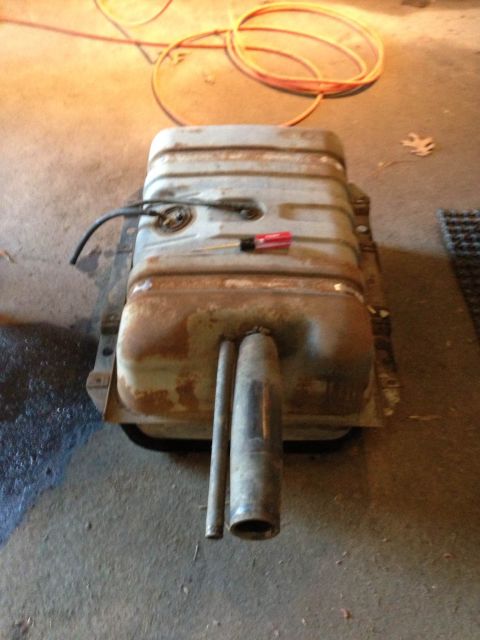 1979 Ford Bronco - This is a detached fuel tank, showing signs of rust and wear, with its associated fuel lines and pump assembly.