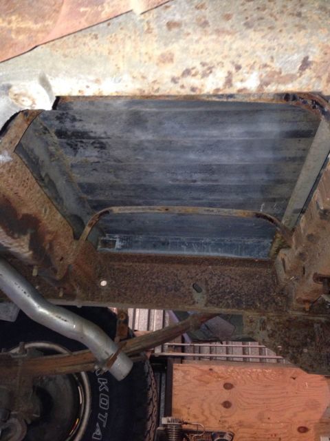 1979 Ford Bronco - The undercarriage of a vehicle shows significant rust and wear, with leaf springs and an exhaust pipe visible.