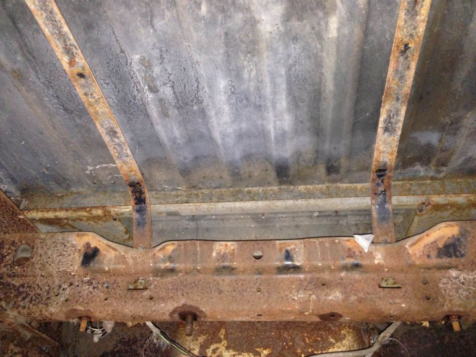 Underside of heavily rusted vehicle frame and bed supports