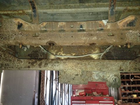 1979 Ford Bronco - Underside view of a vehicle's frame showing significant rust and exposed wiring.