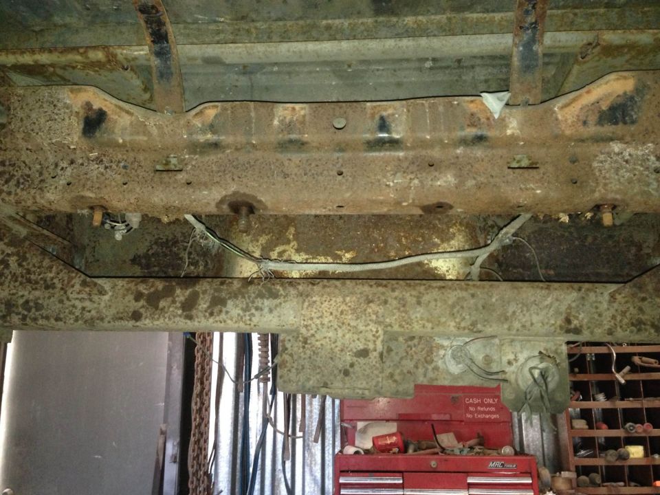Heavily rusted vehicle frame and undercarriage components, with wiring visible