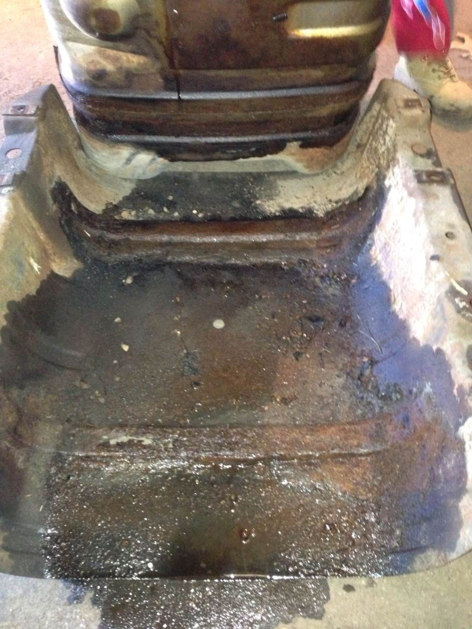 rusted out frame section with oil and grime