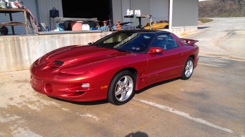1979 Chevrolet Camaro - A red sports coupe with a black t-top roof is parked in front of a garage.
