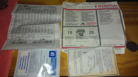 1979 Chevrolet Camaro - Various automotive documents, including a window sticker and build sheet, are laid out on a table.