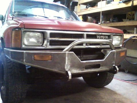 1989 Ford Bronco - Front view of a red Toyota truck a custom metal bumper and brush guard.