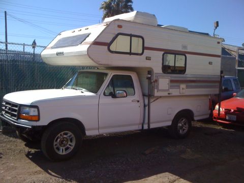 1986 Yugo GV - White pickup truck fitted with a camper shell, parked outdoors.