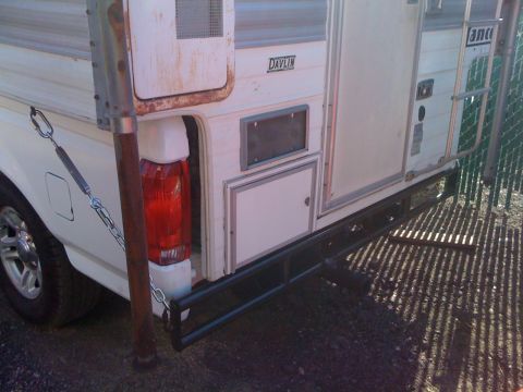1986 Yugo GV - Rear view of a truck camper with a black bumper and support chains visible.