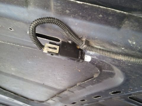 1994 Ford Bronco - A close-up view of a vehicle's underbody wiring harness connector and protective loom.