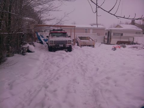 1979 Ford Bronco - A 1979 Ford Bronco sits in a snowy yard next to a trailer and other objects.