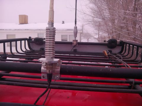 1979 Ford Bronco - Two antennas are mounted on the roof rack of a red vehicle, with a snowy background.
