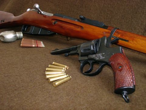 2003 Ford Crown Victoria - A close-up view of a revolver and rifle, accompanied by several rounds of ammunition, arranged on a textured brown background.