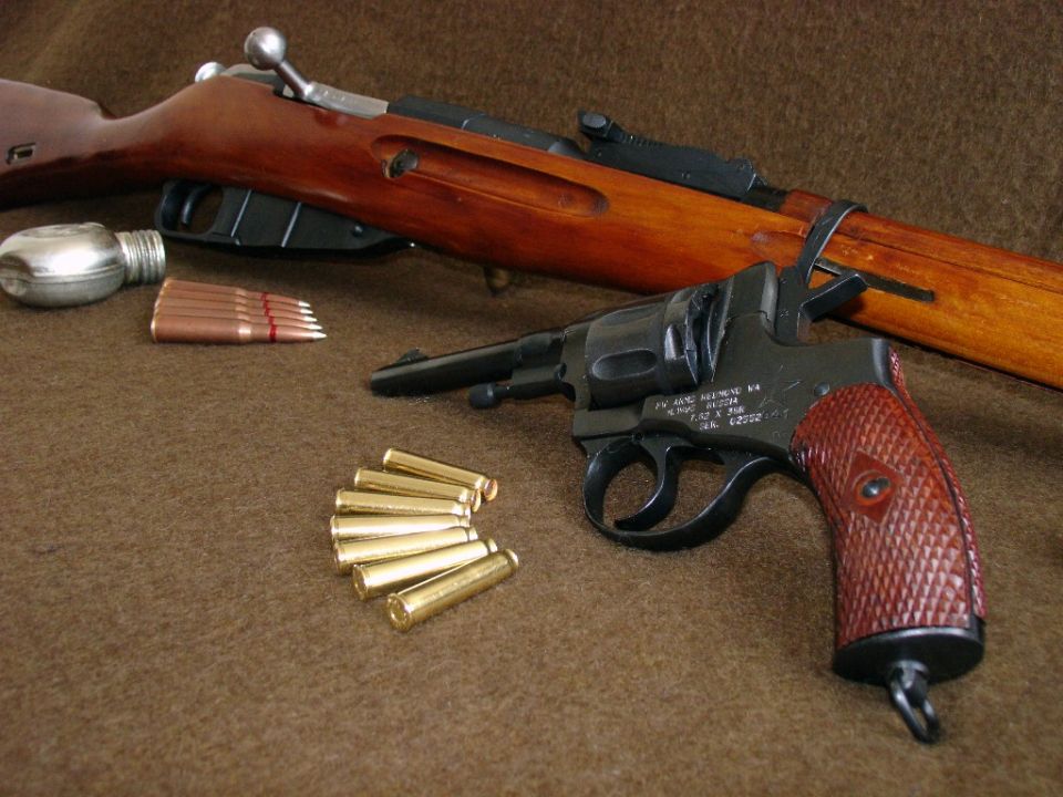 Revolver and rifle with ammunition laid out on a brown surface