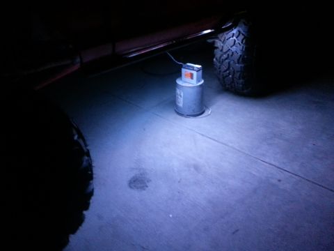 1978 Ford Bronco - Vehicle undercarriage with a rock light installed, casting blue light on the ground.