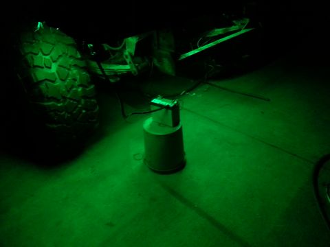 1978 Ford Bronco - A green rock light illuminates the underside of a vehicle, casting a glow on the tire and the ground.