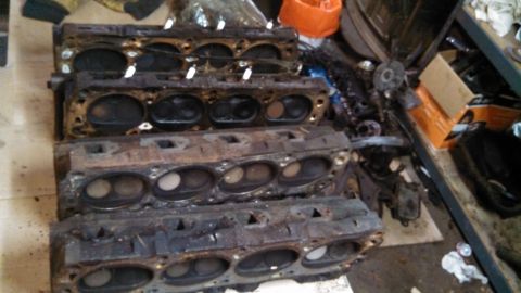 1977 Ford F-150 - Four engine cylinder heads are stacked and appear to be used or in need of rebuilding.