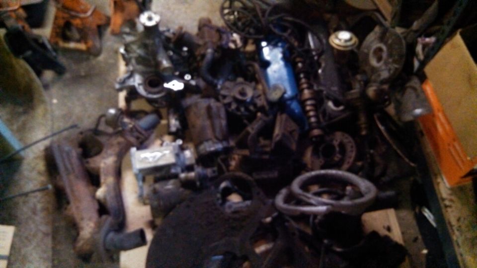 Pile of assorted engine parts including exhaust manifolds and a blue valve cover
