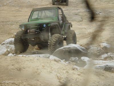 1992 Ford Bronco - An off-road vehicle tackles a challenging course with large rocks and sandy terrain.