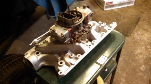 1977 Ford F-150 - A close-up view of an engine's intake manifold and carburetor, likely undergoing maintenance or modification.