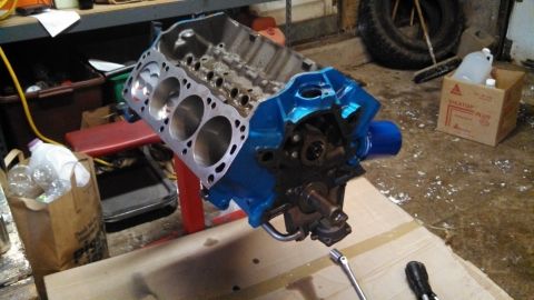 1977 Ford F-150 - A V8 engine block, painted blue, sits on a stand in a workshop setting.