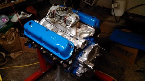 1977 Ford F-150 - A Ford V8 engine with blue valve covers is displayed on a red engine stand.