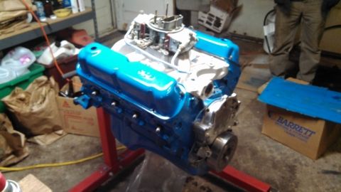 1977 Ford F-150 - A freshly painted V8 engine sits on a stand in a garage setting.