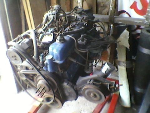1977 Ford F-150 - Engine assembly on a stand, showing belts and pulleys.