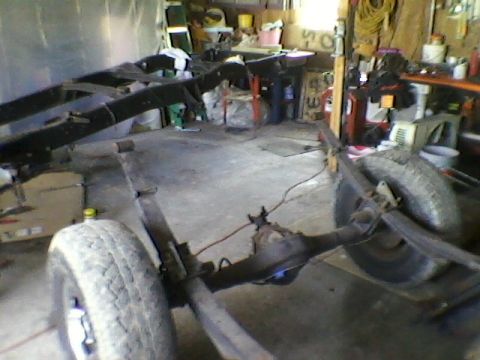 1977 Ford F-150 - The chassis of a truck is shown in a workshop, with parts of the suspension and drivetrain visible.
