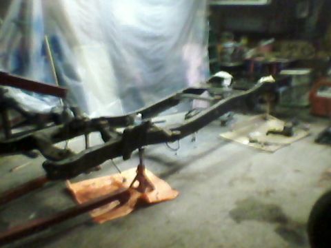 1977 Ford F-150 - The bare frame of a truck is visible, supported by jack stands in a dimly lit garage.