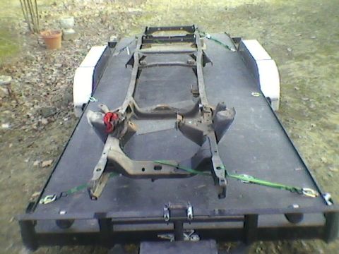 1977 Ford F-150 - A truck frame is transported on a trailer, strapped down for transport.