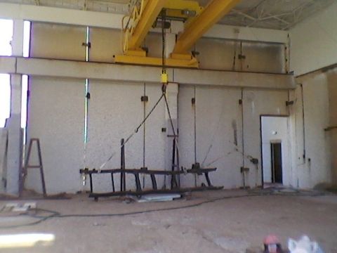 1977 Ford F-150 - An overhead crane is suspended above a load in a large industrial space with concrete walls and a door.