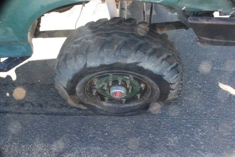 1991 Ford Bronco - A flat tire is visible on the wheel of a green vehicle, showing the hub and tire tread.