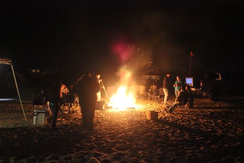 1991 Ford Bronco - Nighttime gathering around a campfire with friends and vehicles in the background.