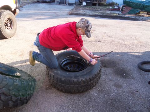1987 Ford Ranger - Person working on changing a tire outdoors with another tire nearby.