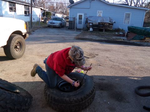 1987 Ford Ranger - A person is working on a large tire in a driveway with a white truck nearby.