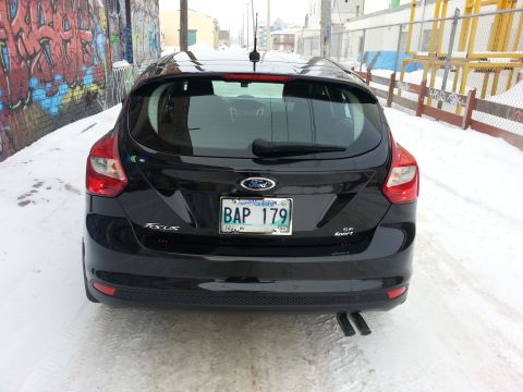 2012 Ford Focus - This black Ford Focus SE Sport hatchback is parked in a snowy alleyway with graffiti on the wall.