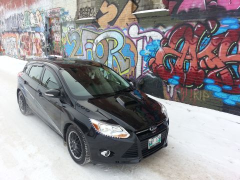 2012 Ford Focus - A black hatchback is parked in front of a wall covered in colorful graffiti, with snow on the ground.