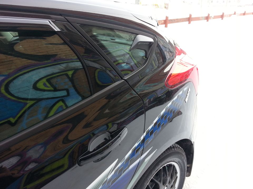2012 Ford Focus rear side view, black paint with graffiti reflected in window