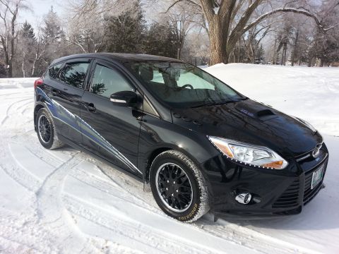 2012 Ford Focus - A black 2012 Ford Focus hatchback with custom graphics and a hood scoop sits in the snow.