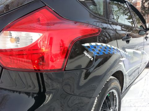 2012 Ford Focus - Rear view of a black 2012 Ford Focus showing the taillight and a checkered racing stripe.
