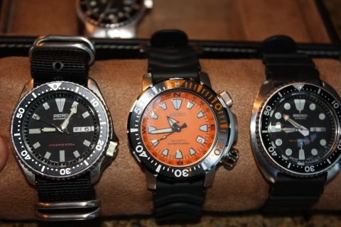 1986 Ford Bronco - Collection of three Seiko automatic dive watches displayed on a brown textured surface.