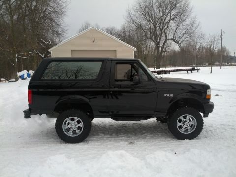 1995 Ford Bronco - A black 1995 Ford Bronco is parked in the snow, showing its side profile.