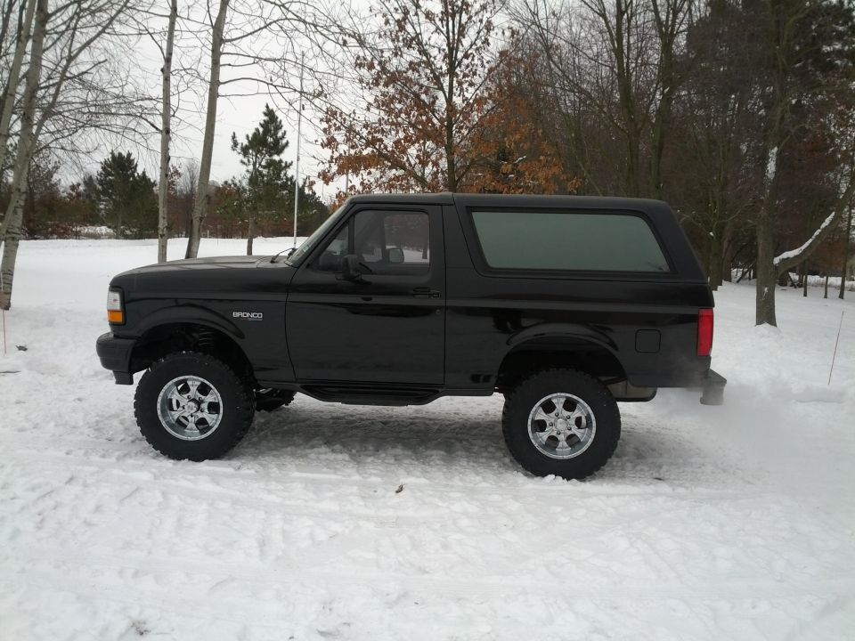 Black Ford Bronco in snow, side view, lifted suspension, aftermarket wheels
