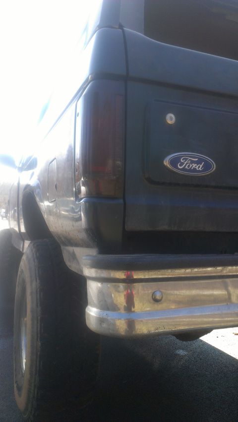 1995 Ford Bronco - Rear view of a dark SUV with a chrome bumper and tinted taillight, showing the Ford emblem.