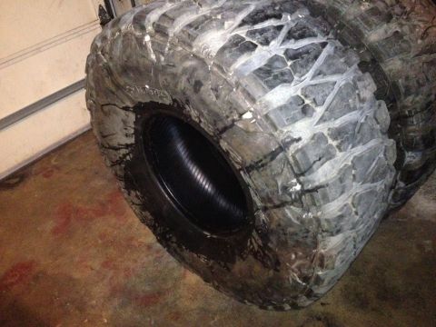 1990 Ford Bronco - Several large off-road tires are stacked, showing their aggressive tread patterns.