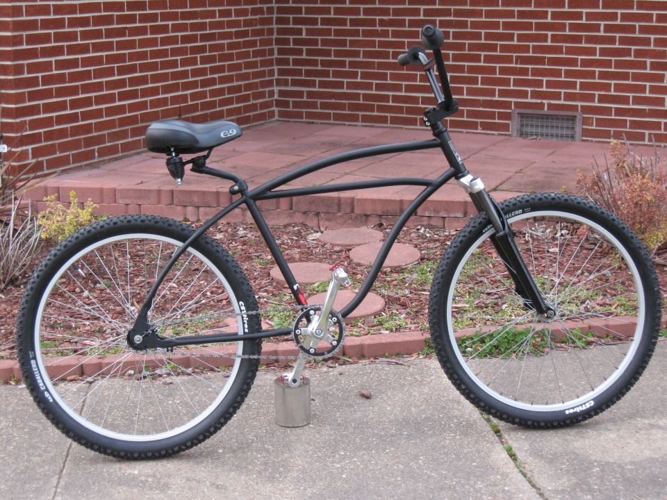 Black cruiser bicycle side view with wide tires and custom pedals