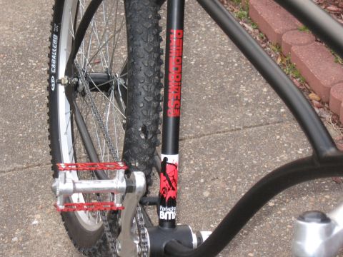 1994 Ford Bronco - Close-up view of a bicycle's frame, red pedals, a knobby tire, and prominent "RATRODBIKES" branding.