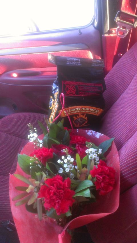1995 Ford Bronco - A bouquet of red flowers and a bag of charcoal sit on the passenger seat of a vehicle.